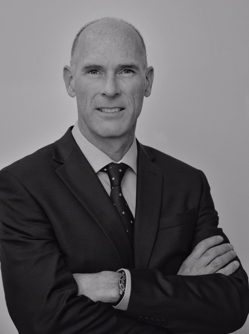 Professional leadership coach in a suit, arms crossed, promoting executive coaching and leadership development.