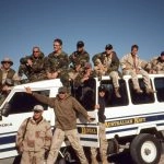 Group of people in military attire on and around a Royal Australian Navy vehicle, leadership and teamwork.