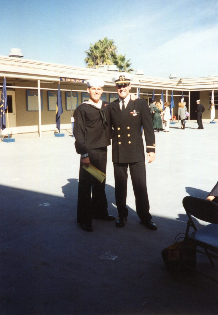 Two individuals in military uniforms at an outdoor event, symbolizing leadership and teamwork.